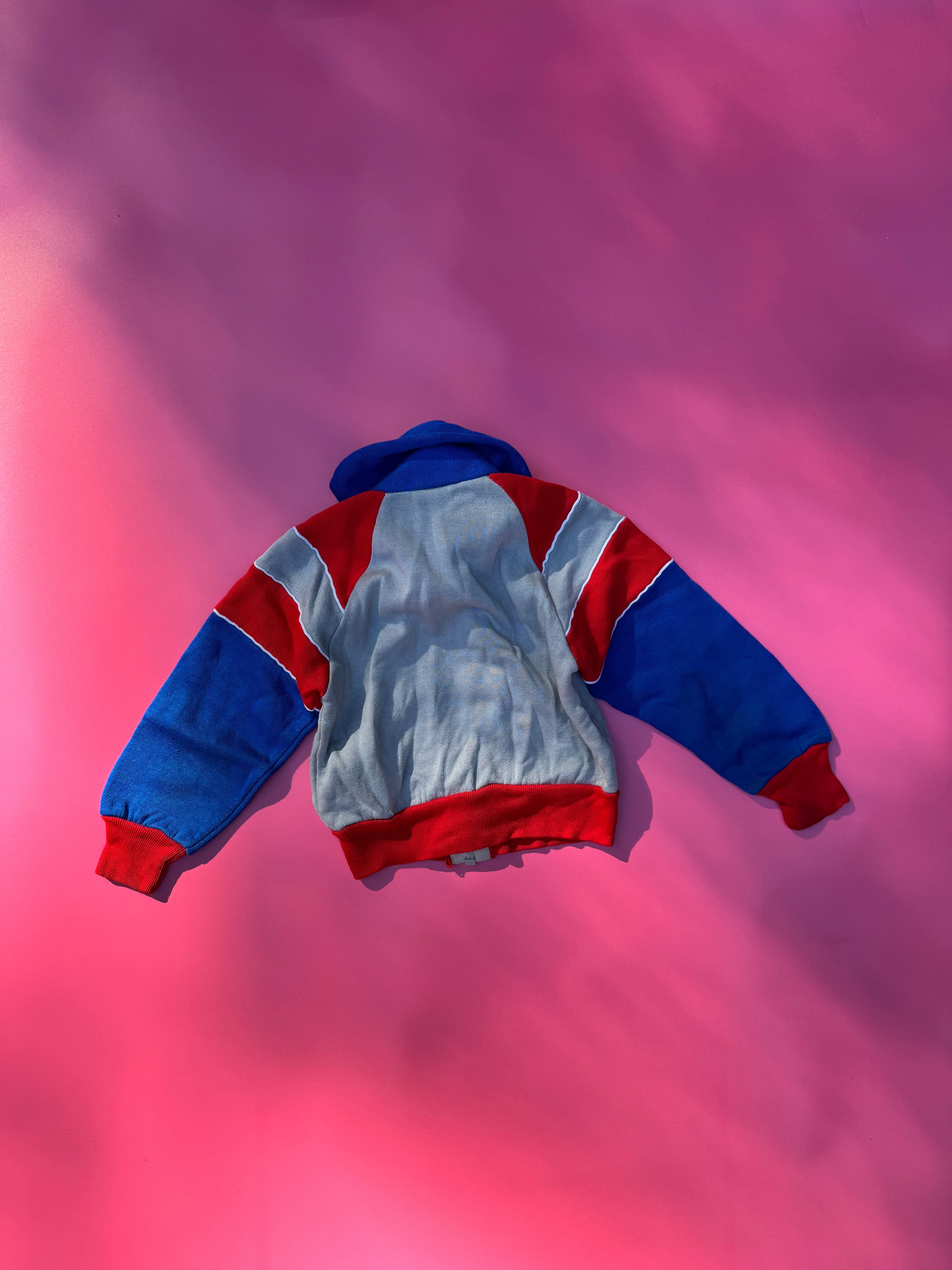 Colorful jacket with red, blue, and gray pattern on a pink and purple gradient background